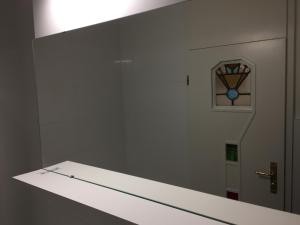 łazienka z lustrem i drzwiami z zegarem w obiekcie City Center Apartment w Monachium