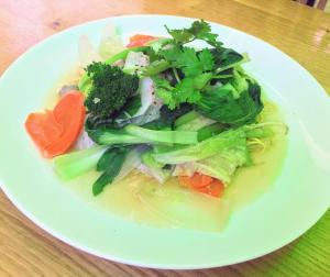 a white plate of food with vegetables on a table at Tony SaiGon Hotel in Ho Chi Minh City