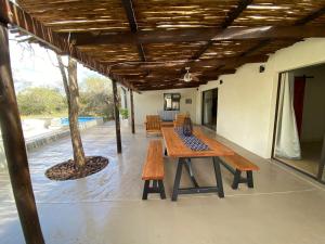 een patio met een houten tafel en banken bij Ostrich Hide in Marloth Park