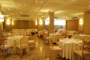 una sala banchetti con tavoli e sedie con biancheria da tavolo bianca di Hotel Bracciotti a Lido di Camaiore