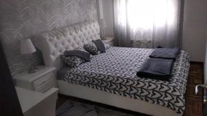 a bed with black and white sheets and a window at Lux Apartman Ristić 1 in Soko Banja