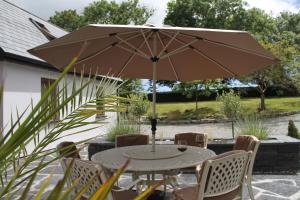 a table and chairs with an umbrella on a patio at Boatman's Quarters in Skibbereen