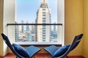 two chairs in front of a window with a view of a city at Luxe, spacious, 2BD Condo with Full kitchen, Marina View, Steps from JBR Beach, Tram & Marina by "La Buena Vida Holiday Homes" in Dubai