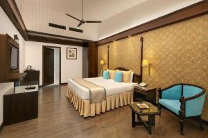 - une chambre avec un grand lit et une chaise bleue dans l'établissement Shervani Hilltop Resort, à Nainital