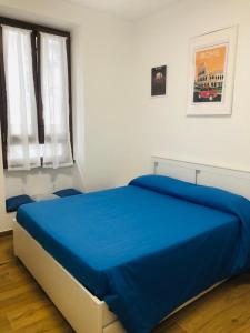 uma cama azul num quarto branco com uma janela em DomuSumma em Roma