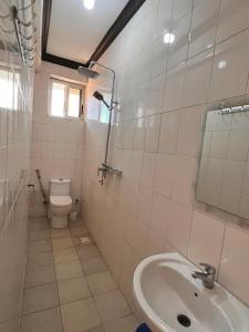 a white bathroom with a sink and a toilet at Haika Home Lodge in Dar es Salaam