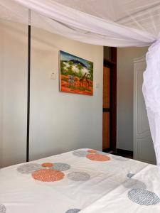 a bedroom with a white bed with a painting on the wall at Haika Home Lodge in Dar es Salaam