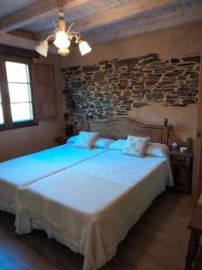 a bedroom with a large white bed with a stone wall at VUT El Pajariel Ponferrada in Ponferrada