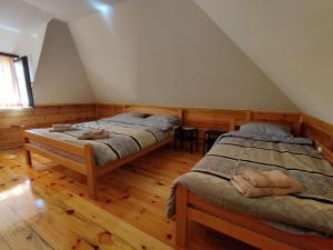 Zaovine的住宿－Milijin konak，铺有木地板的客房内的两张床