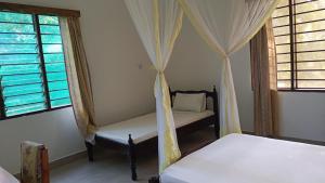 a bedroom with two beds and two windows at Makuti Villas Resort in Kilifi
