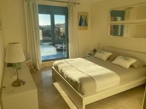 1 dormitorio con cama y ventana grande en Apartamento con terraza sobre La Marina de Sotogrande, en San Roque