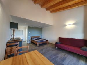 a living room with a red couch and a bed at Agriturismo Budin in Sgonico
