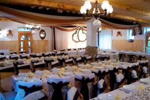 un gran salón de banquetes con mesas y sillas blancas en Felső Fogadó en Felsőtold