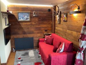 un sofá rojo en una habitación con paredes de madera en Baita del Cervino CIR n 0016, en Breuil-Cervinia