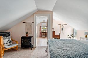 1 dormitorio con 1 cama y 1 silla en el ático en Sunroom on Maple, en Picton