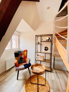 Cette chambre comprend une chaise, une table et des étagères. dans l'établissement L'Envolée Alsacienne - Magnifique appartement en duplex, à Ostheim