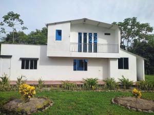 ein weißes Haus mit einem Balkon im Hof in der Unterkunft Villas Campestres las Heliconias - Villa Ginger in Villavicencio
