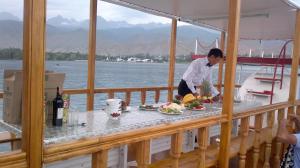 a man preparing food on a balcony on a boat at Asfandiar Hotel in Karakol +26 photos