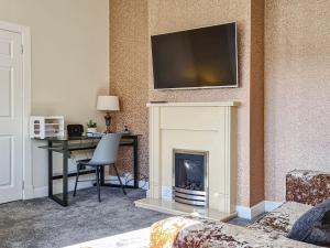 a living room with a fireplace with a television above it at Kirklea in Wishaw