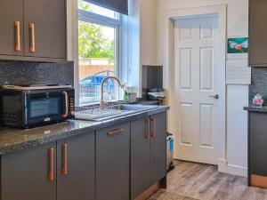 uma cozinha com um lavatório e um micro-ondas em Kirklea em Wishaw