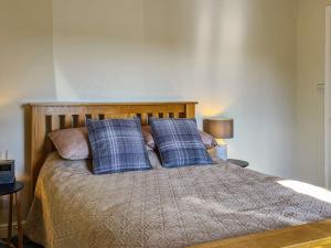 uma cama com almofadas azuis e cor-de-rosa em Kirklea em Wishaw