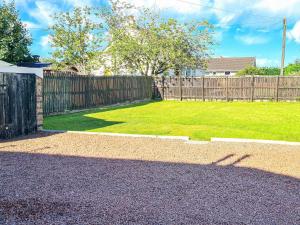 a backyard with a wooden fence and a green lawn at Kirklea in Wishaw