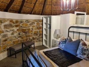 a bedroom with a bed and a stone wall at Burnbrae Farmhouse (6 b/rooms with pool) in Himeville