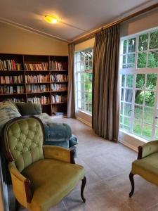 a living room with a couch and bookshelves at Burnbrae Farmhouse (6 b/rooms with pool) in Himeville