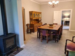 a dining room with a table and a wood stove at Burnbrae Farmhouse (6 b/rooms with pool) in Himeville