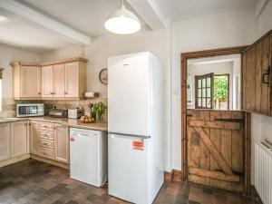 a kitchen with a white refrigerator and wooden cabinets at Home Farm House in Dorrington