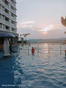 a swimming pool with people in the water next to a building at Sri Kejora Vista Bangi Homestay -Studio in Kajang