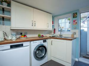 a kitchen with white cabinets and a washing machine at Coastal Haven in Dawlish