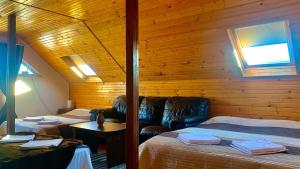 a room with two beds and a leather couch at Cabana Plaiuri Ardelene in Petreştii de Jos
