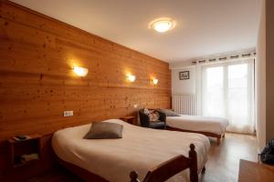 um quarto com 2 camas e uma parede de madeira em Logis Hôtel Restaurant L'ancienne Auberge em Bolquere Pyrenees 2000