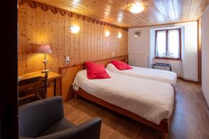 a bedroom with two beds and a chair in it at Logis Hôtel Restaurant L'ancienne Auberge in Bolquere Pyrenees 2000