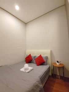 a small bedroom with a bed with red pillows at Inspired Homes @ KLCC Soho Suite in Kuala Lumpur