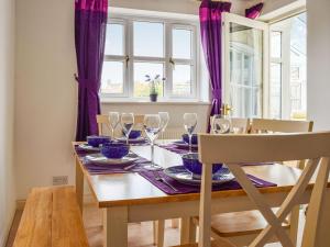 uma sala de jantar com uma mesa com copos de vinho em Primrose Cottage em Little Rissington