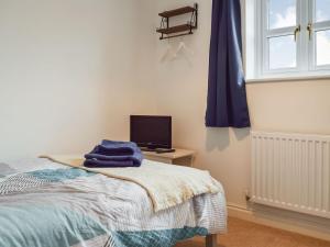 um quarto com uma cama e uma secretária com uma televisão em Primrose Cottage em Little Rissington