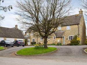 a house with a tree in the middle of a street at Primrose Cottage in Little Rissington