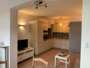 uma cozinha com armários brancos, uma televisão e uma mesa em LA REPOSADE em Sanary-sur-Mer