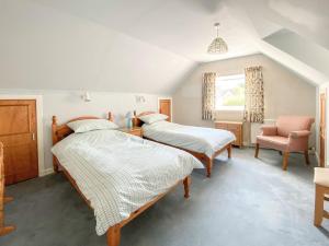 a bedroom with two beds and a chair at Inverwick Cottage in Nairn