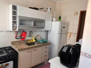 a small kitchen with a sink and a refrigerator at Residencial Michelângelo in Mongaguá
