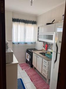 a small kitchen with a stove and a refrigerator at Residencial Michelângelo in Mongaguá