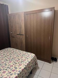 a bedroom with a bed and two wooden cabinets at Residencial Michelângelo in Mongaguá