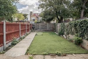 a yard with a fence andgrass at Impeccable and welcoming 3-Bed House in London in London