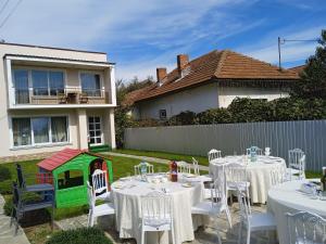 a garden with white tables and chairs and a play house at CASA SONIA in Târgu Jiu