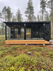 a black house with a wooden deck in a field at SiikaVilla, Siikajoki in Siikajoki