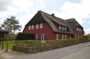 une maison rouge avec un toit de chaume dans l'établissement Mühlenhaus 3, à Wrixum