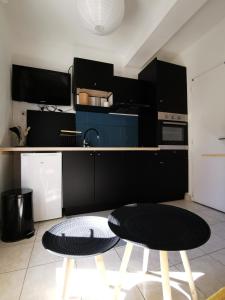 a kitchen with black cabinets and a table and two chairs at Mèze, charmant petit studio proche port in Mèze