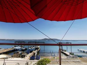 a red umbrella in front of a marina with boats at Mèze, charmant petit studio proche port in Mèze